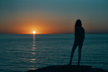 Fototapeta premium silhouette of woman on the sea at sunset and skyline beach sky