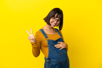 Young pregnant woman over isolated yellow background showing victory sign with both hands