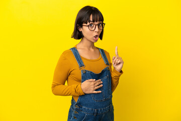 Young pregnant woman over isolated yellow background intending to realizes the solution while lifting a finger up