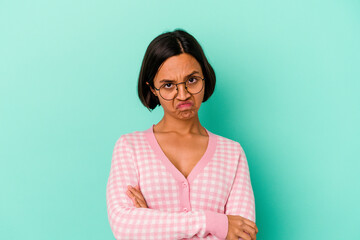 Young mixed race woman isolated on blue background frowning face in displeasure, keeps arms folded.