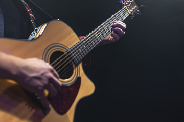 Obraz na płótnie Canvas Guitarist playing acoustic guitar in the dark.