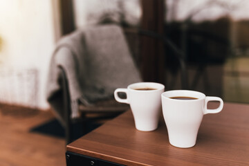 Two cups of coffee on the table on wooden brown terrace during evening sunset