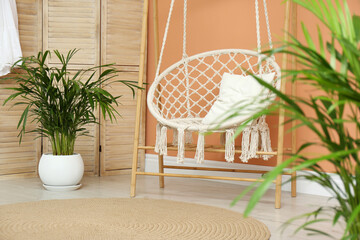 Beautiful exotic house plants and swing chair in room. Interior design