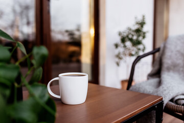 Cup of coffee or tea on the table on the wooden brown terrace during sunset