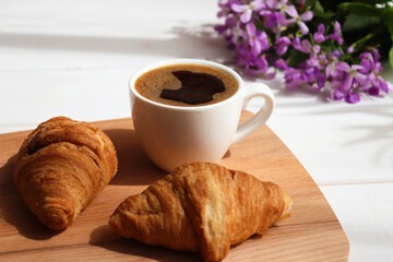 Coffee with croissants and flowers on the table. Delicious breakfast, start of the day. Morning concept. Close-up, selective focus