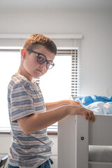 Portrait of a little boy with glasses in his room.