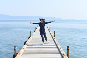 Fototapeta na wymiar 45 y.o. Russian woman running on a wooden pier by the Japanese sea
