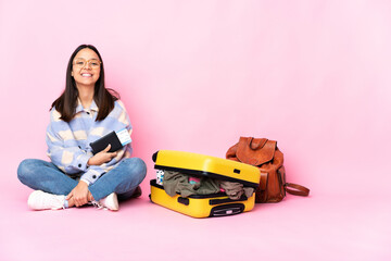 Traveler woman with a suitcase sitting on the floor keeping the arms crossed in frontal position