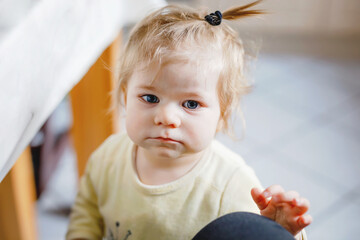 Naklejka premium Little baby girl learning walking, standing and making first steps at home. Toddler balancing. Happy child, balance and development
