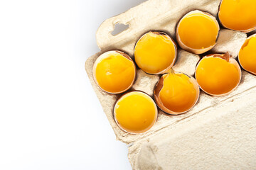 Close-up of fresh chicken eggs yolks in a shell on cardboard tray. Top view. Flat lay