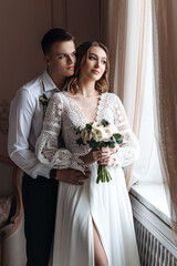 Portrait of the bride and groom in a lace dress in boho style with a bouquet.