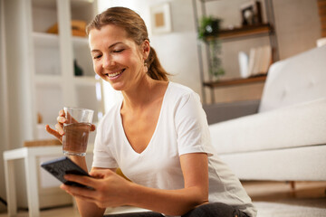 Girl holding a glass of water. Smiling girl drinking water.