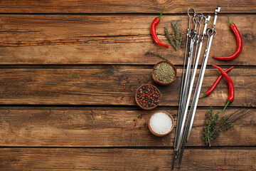 Flat lay composition with metal skewers on wooden table. Space for text