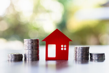 Red houses and a pile of coins. Home based loan ideas. Money from business finance coins. Successful financial business. Savings for a miniature model real estate project.