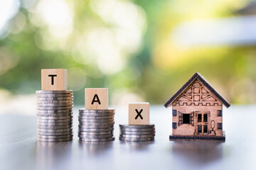 A model house, the word tax is placed on top of the coin pile. House tax. Housing tax.