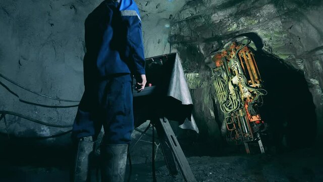 Industrial worker is operating a boring mechanism in the mine