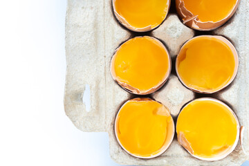 Close-up of fresh chicken eggs yolks in a shell on cardboard tray. Top view. Flat lay