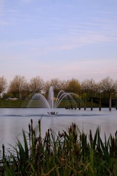 View of a  water fountain in a lake with a blue sky in the background in Bussy Saint Georges France