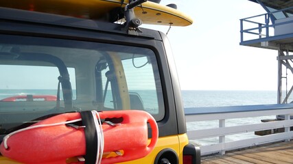 Yellow lifeguard car, San Clemente beach pier, California USA. Coastline rescue life guard pick up truck, lifesavers vehicle. Auto and ocean coast. Los Angeles vibes, summertime aesthetic atmosphere.