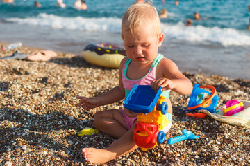 Baby Girl Sits on Sandy Pebble Beach