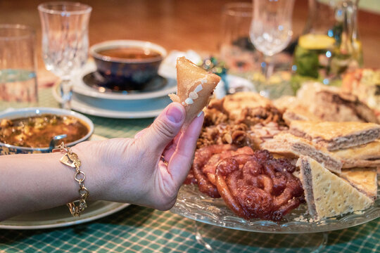 ONE HAND OF AN ADULT WEARS RING AND BRACELET OVER BOWL OF HEALTHY VEGETABLE SOUP, ONE HAND GRASPS A DATE IN THE BACKGROUND OF OTHER FOOD DISHES, close up