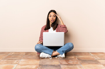 Young mixed race woman with a laptop sitting on the floor has realized something and intending the solution