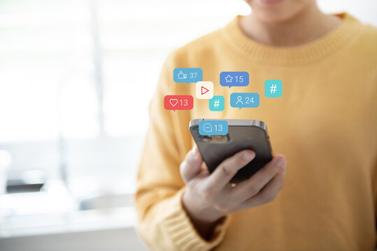 Happy woman using a social media marketing concept on mobile smartphone with notification icons of love, like, message, comment and hashtag.
