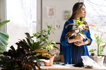 Young woman florist taking care of pot plants