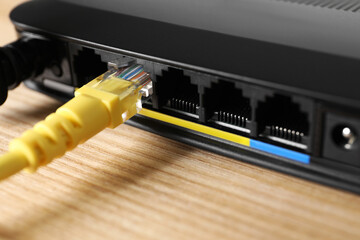 Connected cable to router on wooden table, closeup. Wireless internet communication