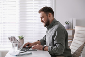 Young man working on laptop at table in office