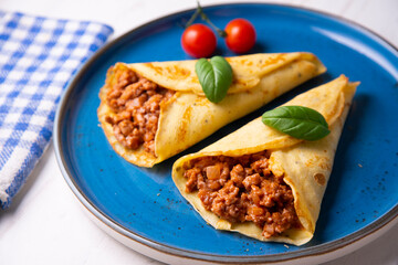 Crepes stuffed with bolognese sauce and basilicum leaves