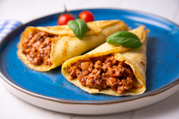 Crepes stuffed with bolognese sauce and basilicum leaves