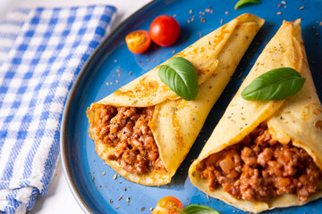 Crepes stuffed with bolognese sauce and basilicum leaves