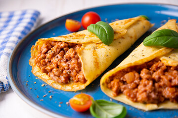 Crepes stuffed with bolognese sauce and basilicum leaves