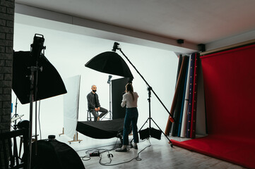Professional photographer working in the studio with a male model on a white background.