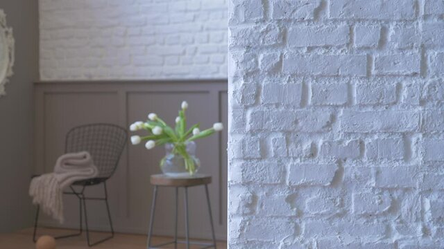 Vase of plant flower background with white brick wall close up, black chair mirror and blanket style.
