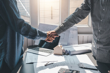 Architects and contractors shaking hands work deals on building a house together using a laptop...