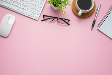 Top view of pink workspace with coffee keyboard notebook glasses copy space paste flat.