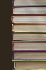 The covers of colorful books in a stack on a dark background. Rainbow stack of books. Book pages. Library study and knowledge