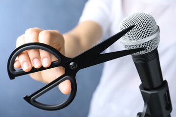 Woman making ASMR sounds with microphone and scissors on blue background, closeup