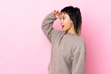 Young Uruguayan woman over isolated pink background with surprise expression while looking side