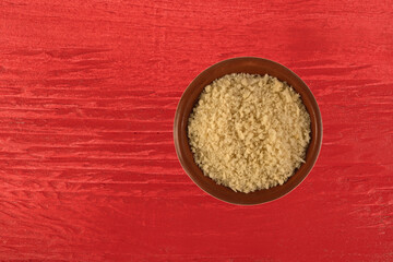 Terracotta bowl filled with white bread crumbs on a bright red wood painted background top view.