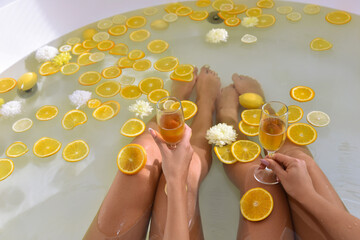 Two woman with two glasses of champagne taking bath.