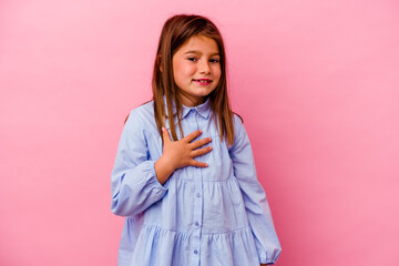 Little caucasian girl isolated on pink background  laughs out loudly keeping hand on chest.