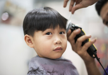 little asian boy having a haircut at barbershop : close up