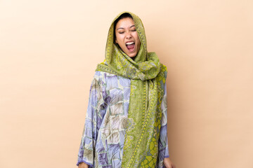 Indian woman isolated on beige background shouting to the front with mouth wide open