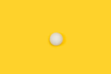 Una pelota blanca de tenis de mesa ping pong sobre un fondo amarillo liso y aislado. Vista superior. Copy space. Concepto: Deportes