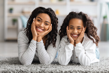 Adorable african american mother and daughter posing on carpet