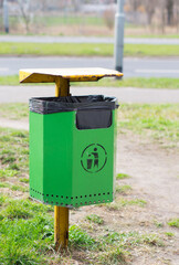 POZNA, POLAND - Apr 08, 2015: Green trash bin at a park - obrazy, fototapety, plakaty