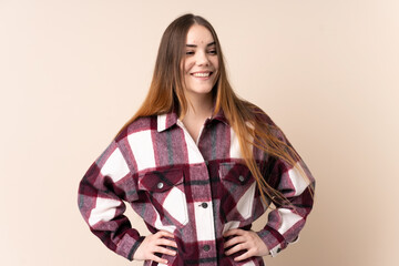 Naklejka premium Young caucasian woman isolated on beige background posing with arms at hip and smiling